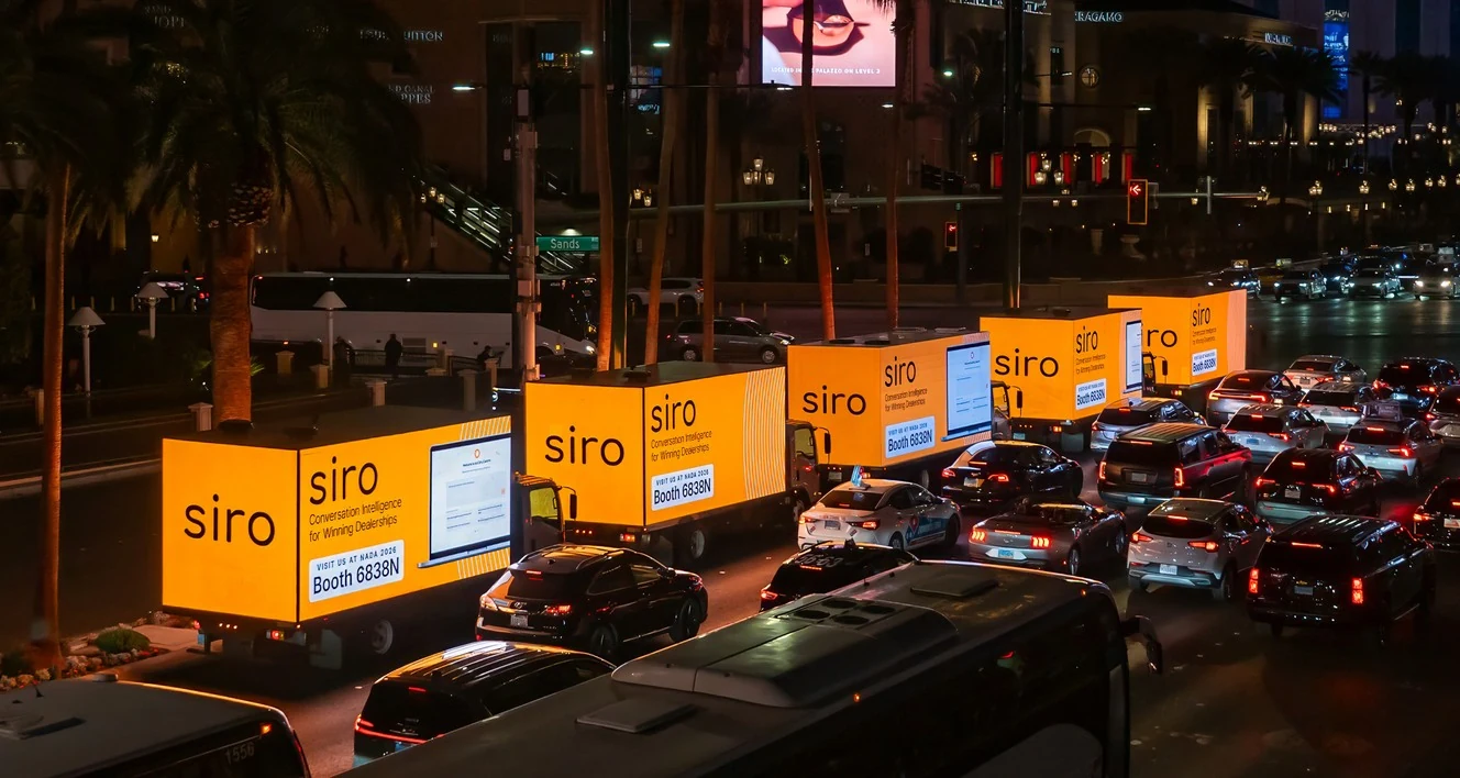 A line of illuminated advertising trucks on the Las Vegas Strip at night