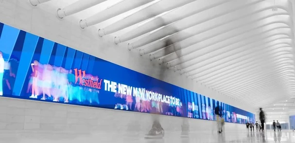 A row of digital screens along a bright indoor walkway